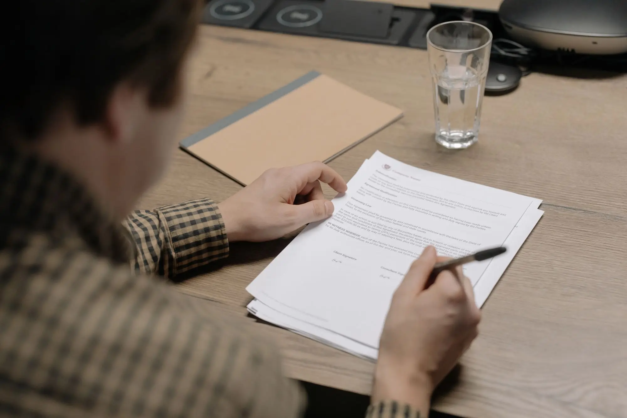 Business owner at a meeting-room desk rereading a signed loan agreement with a pen in hand