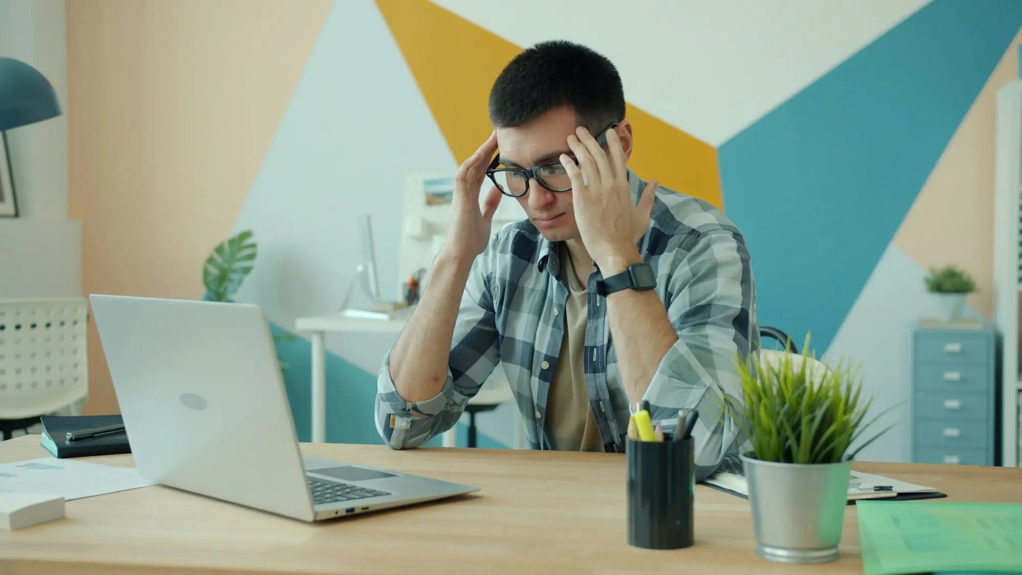 Small business owner with hands on head at a desk, reading an unfamiliar credit enquiry on a laptop screen